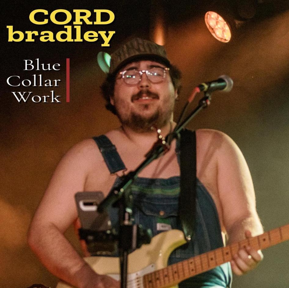 Blue Collar Work — Cord Bradley on stage in denim overalls under amber light, playing a butterscotch Telecaster.